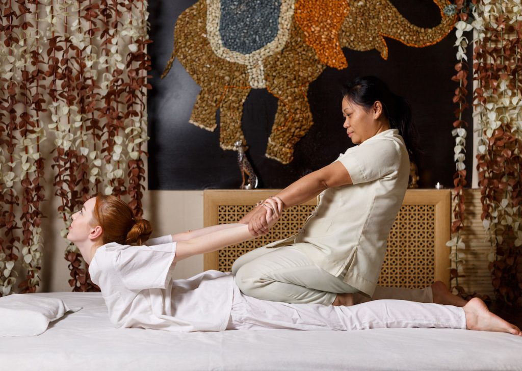 Young-female-receiving-massage-by-therapist-in-traditional-Thai-position-1200x853